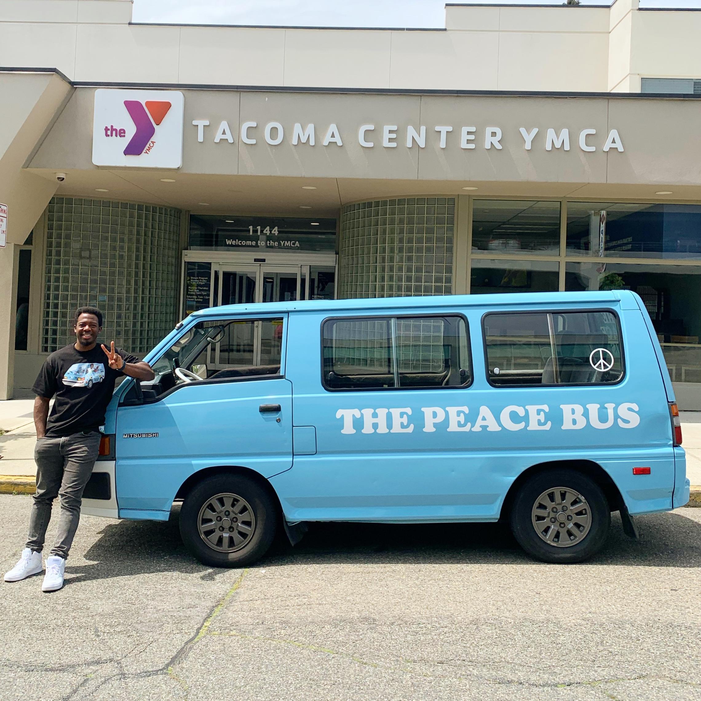 Kwabi stands with his bus in front of Tacoma Center YMCA