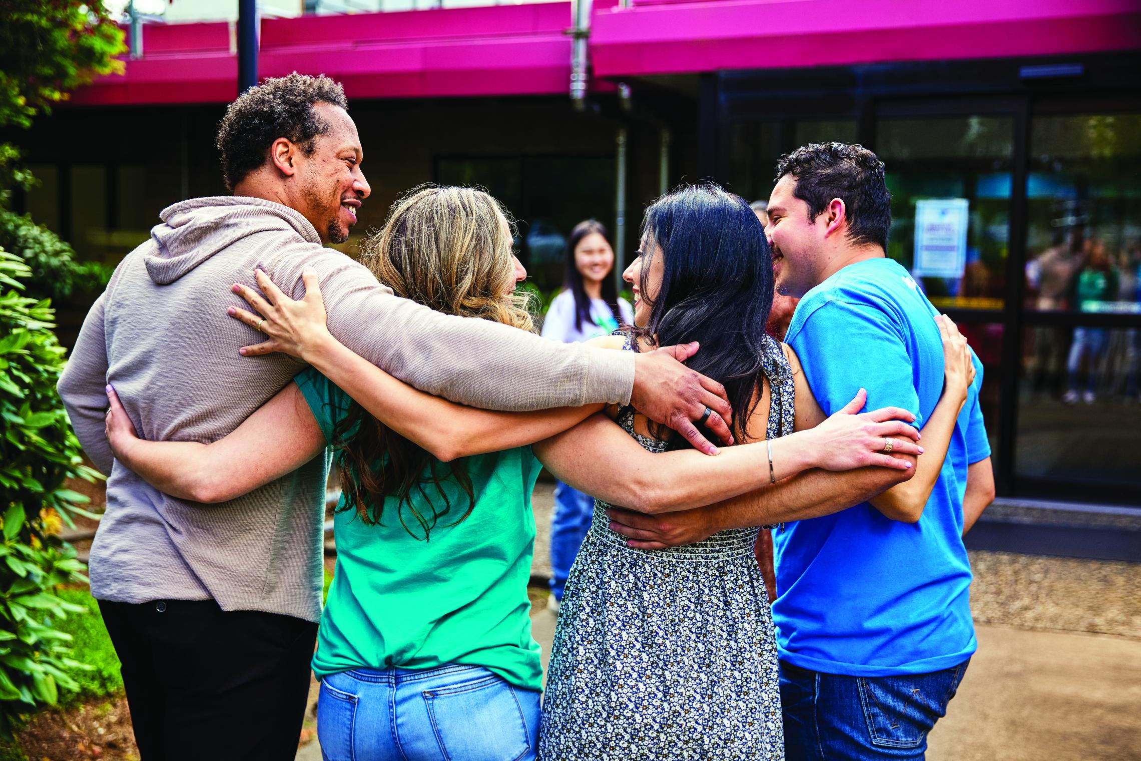 A group of four people gather in front of a YMCA community center