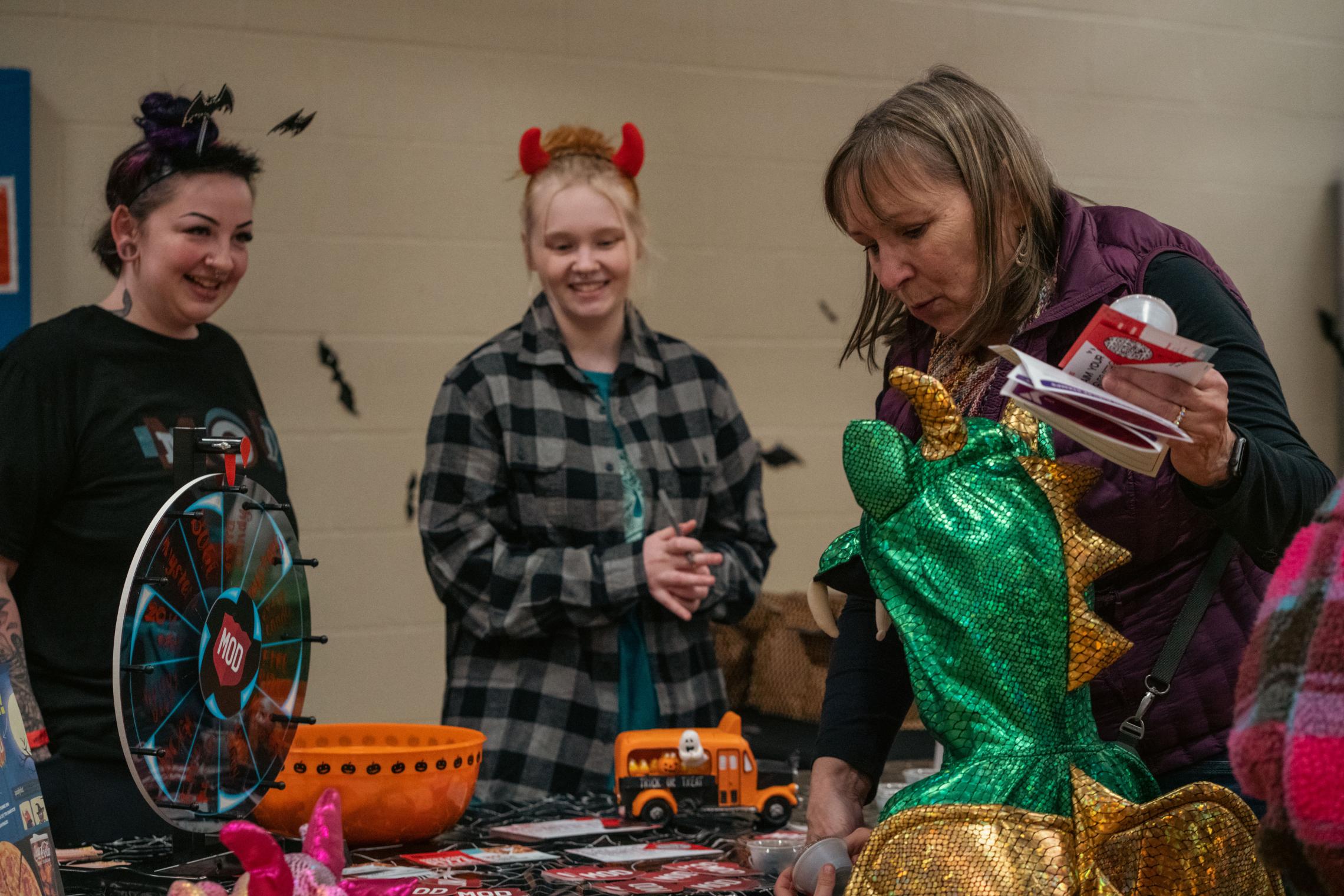 A child dressed as a holographic dragon visits a table of community partners in Tacoma. 