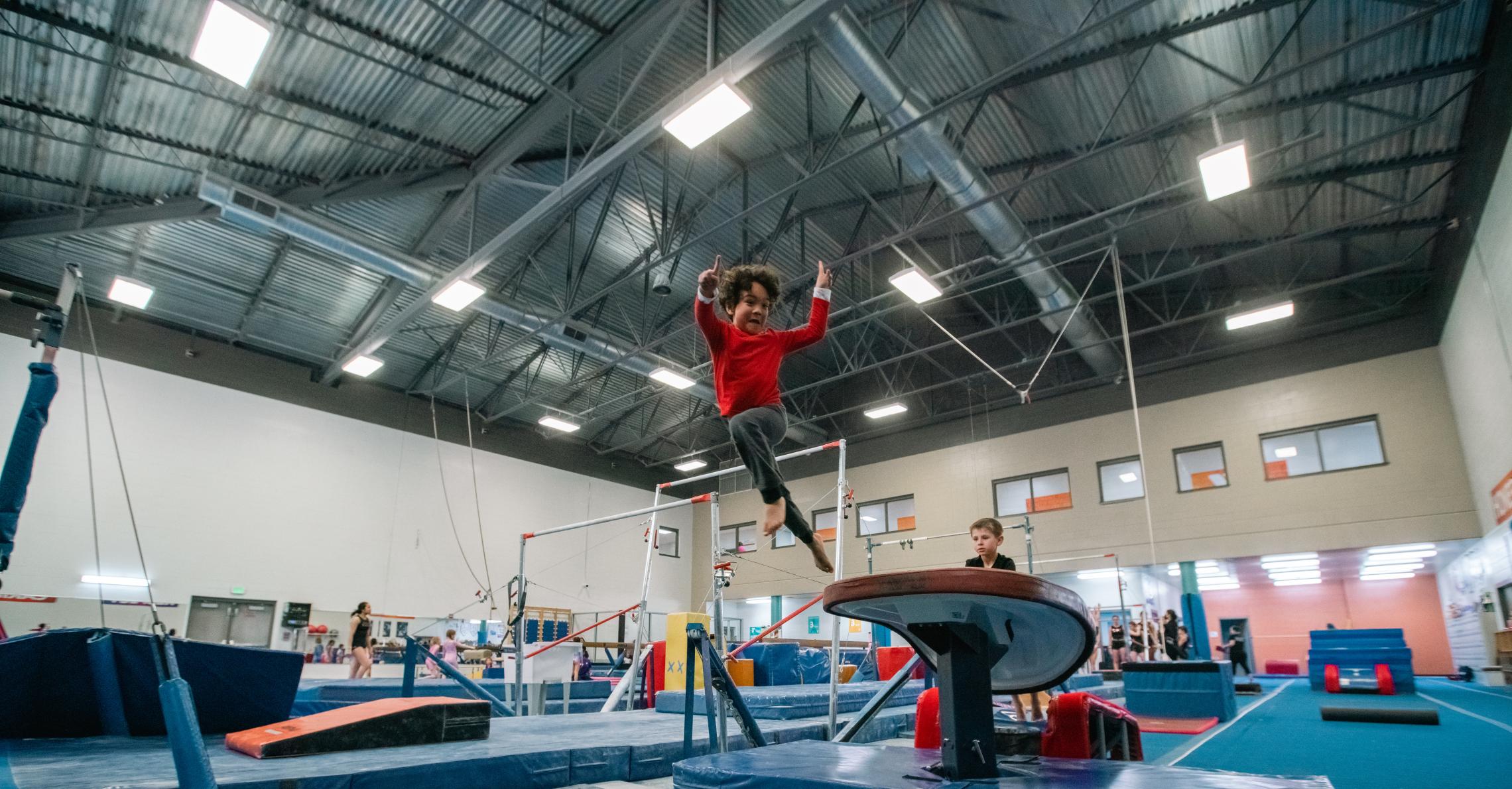 Youth gymnastics participant posing off a jump off the spring board at the YMCA