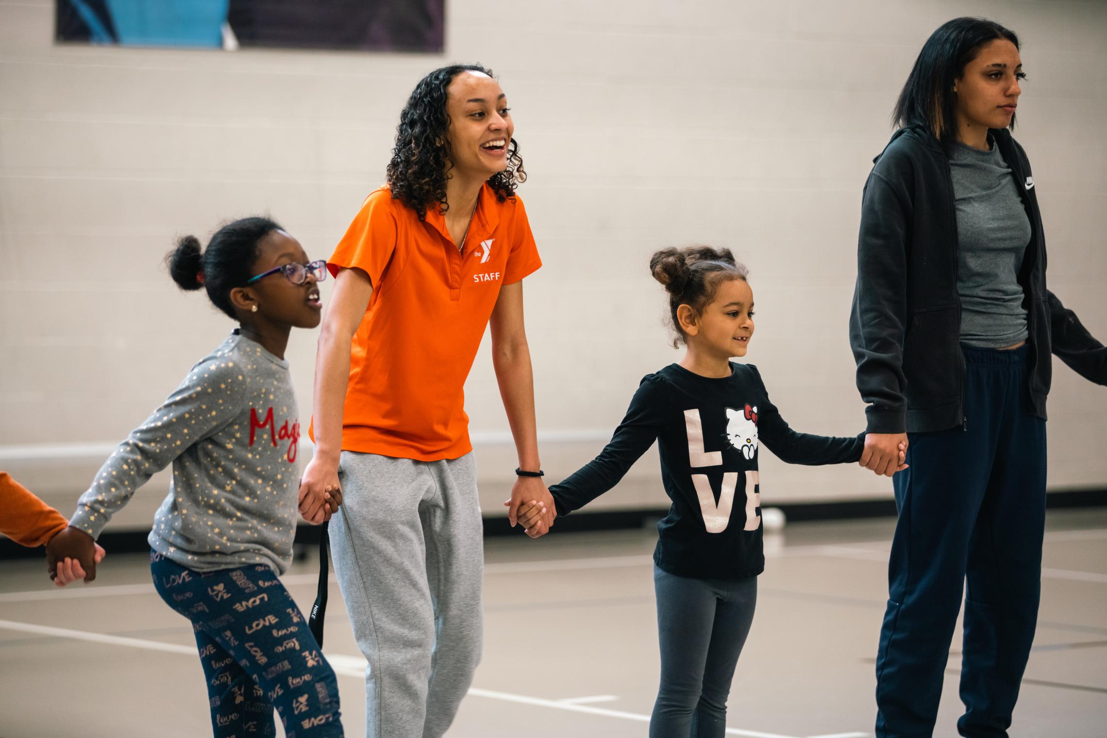 Camp participants and counsellors link hands in a game at the YMCA