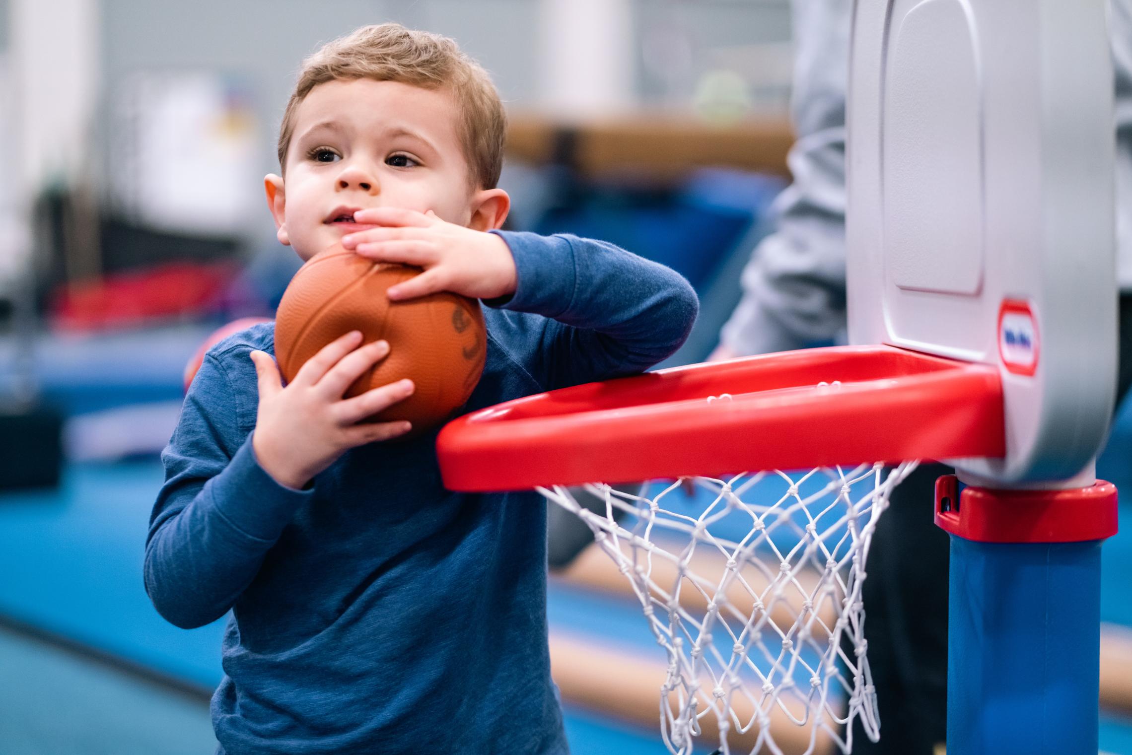 YMCA Child care toddler playing with a toy basketball and hoop