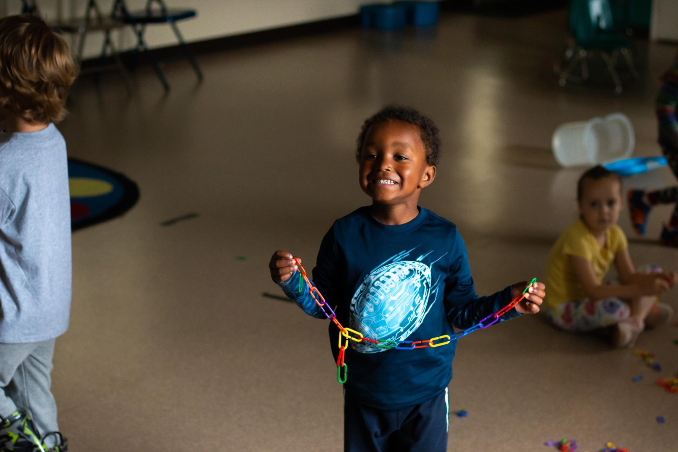 Summer camp participant holding up a colorful toy chain link while playing at they YMCA