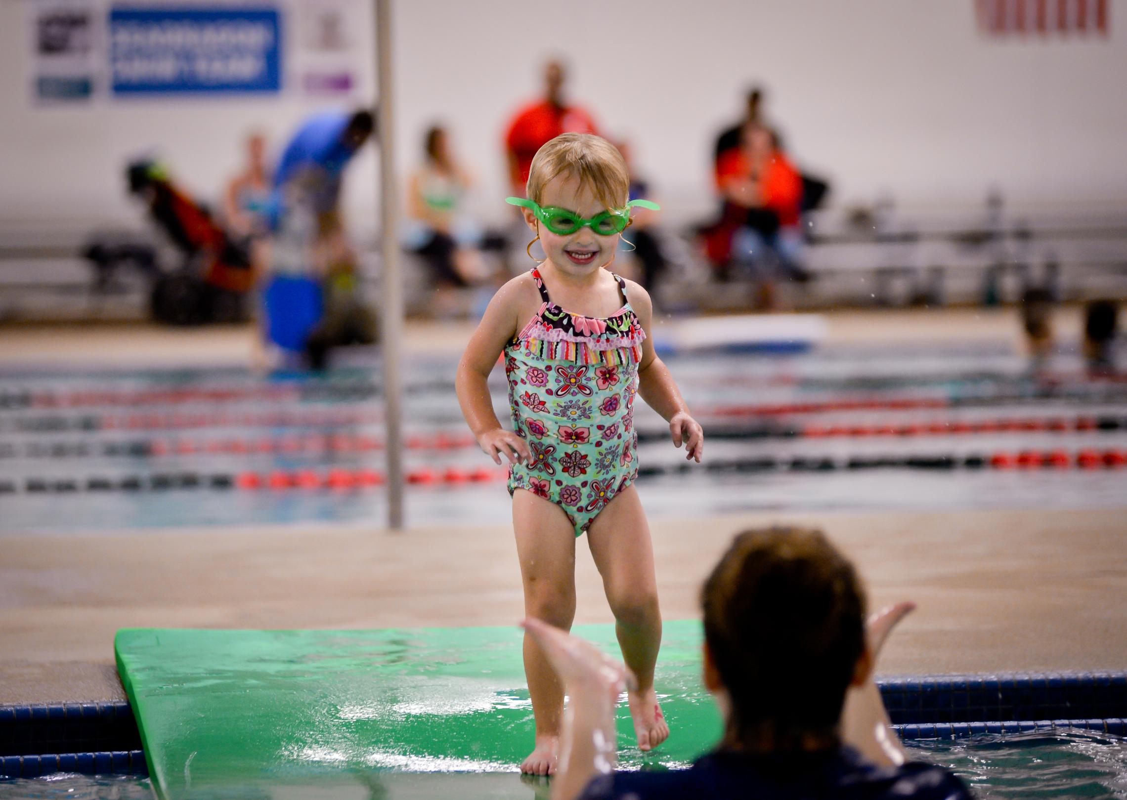 Toddler swim student jumps into the pool toward their instructor at the YMCA