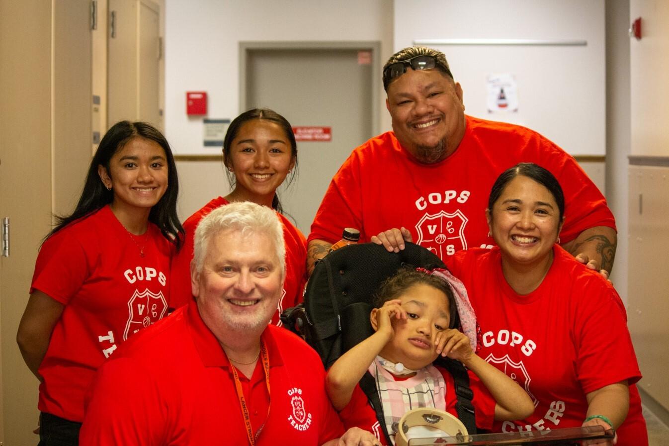 Cops vs Teachers charity participants smile in matching T-shirts at the YMCA