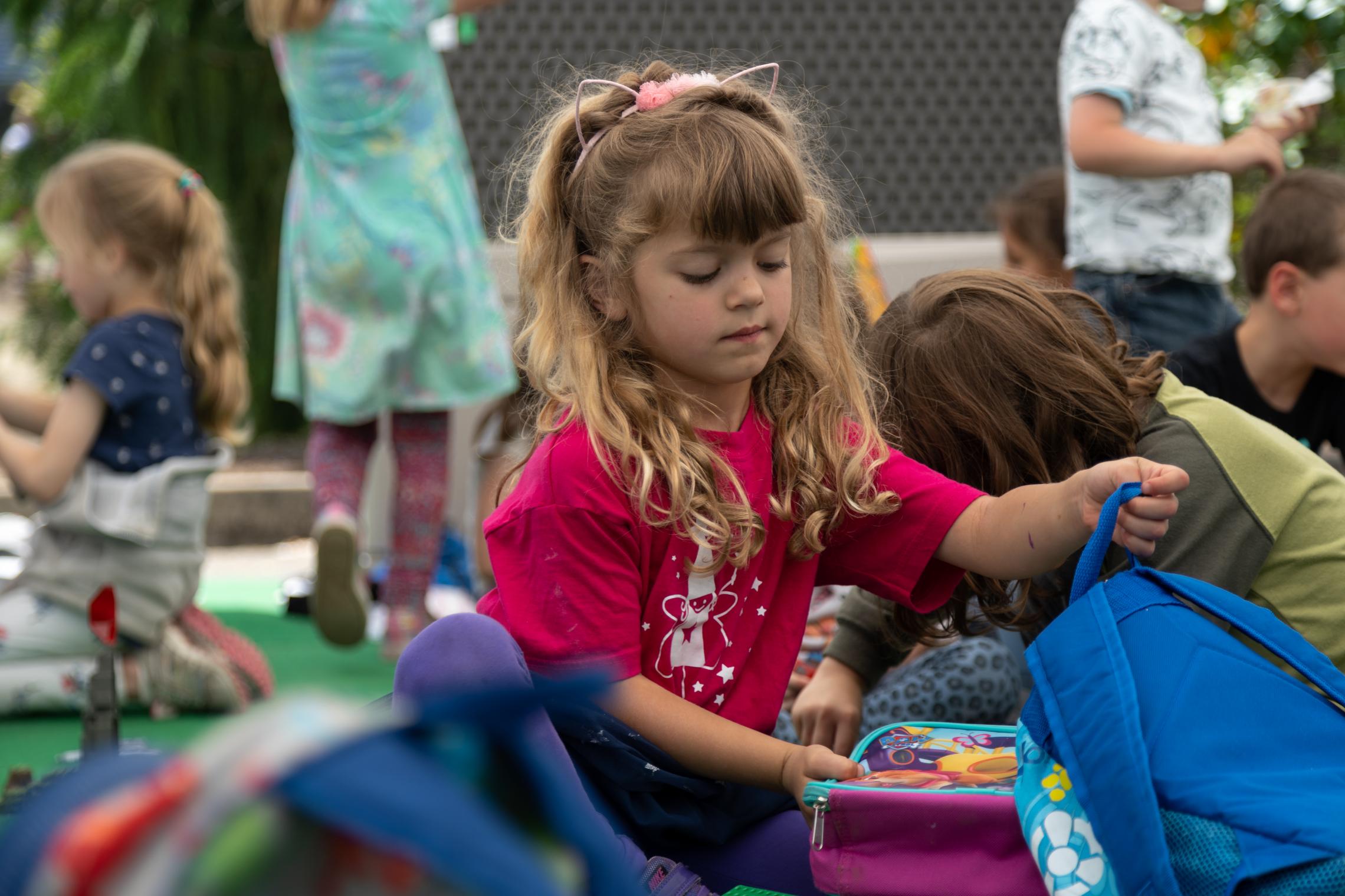 Summer camp participants pulls lunchbox from her backpack during snack time at they YMCA