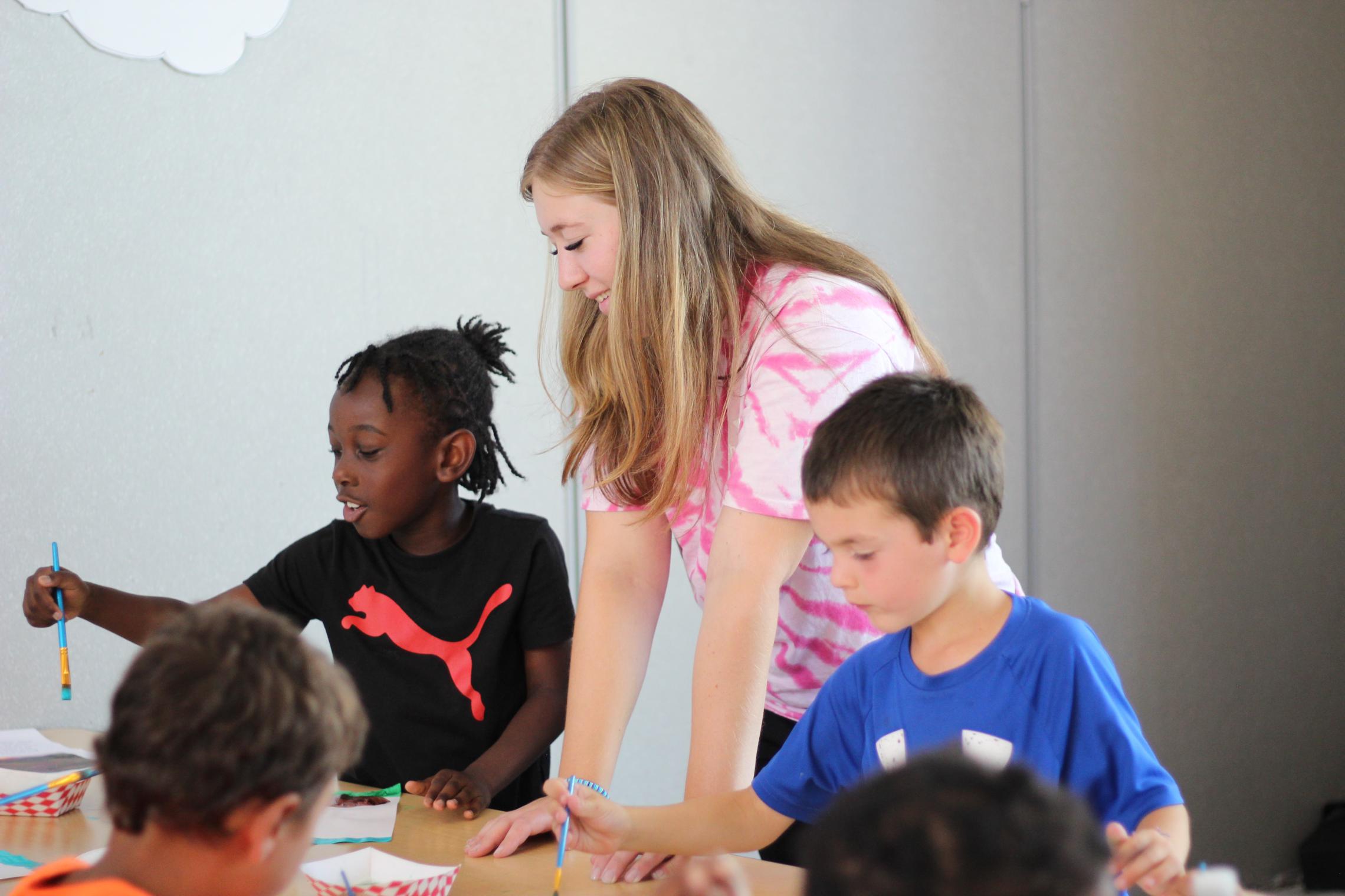 Child care staff leads painting time at the YMCA