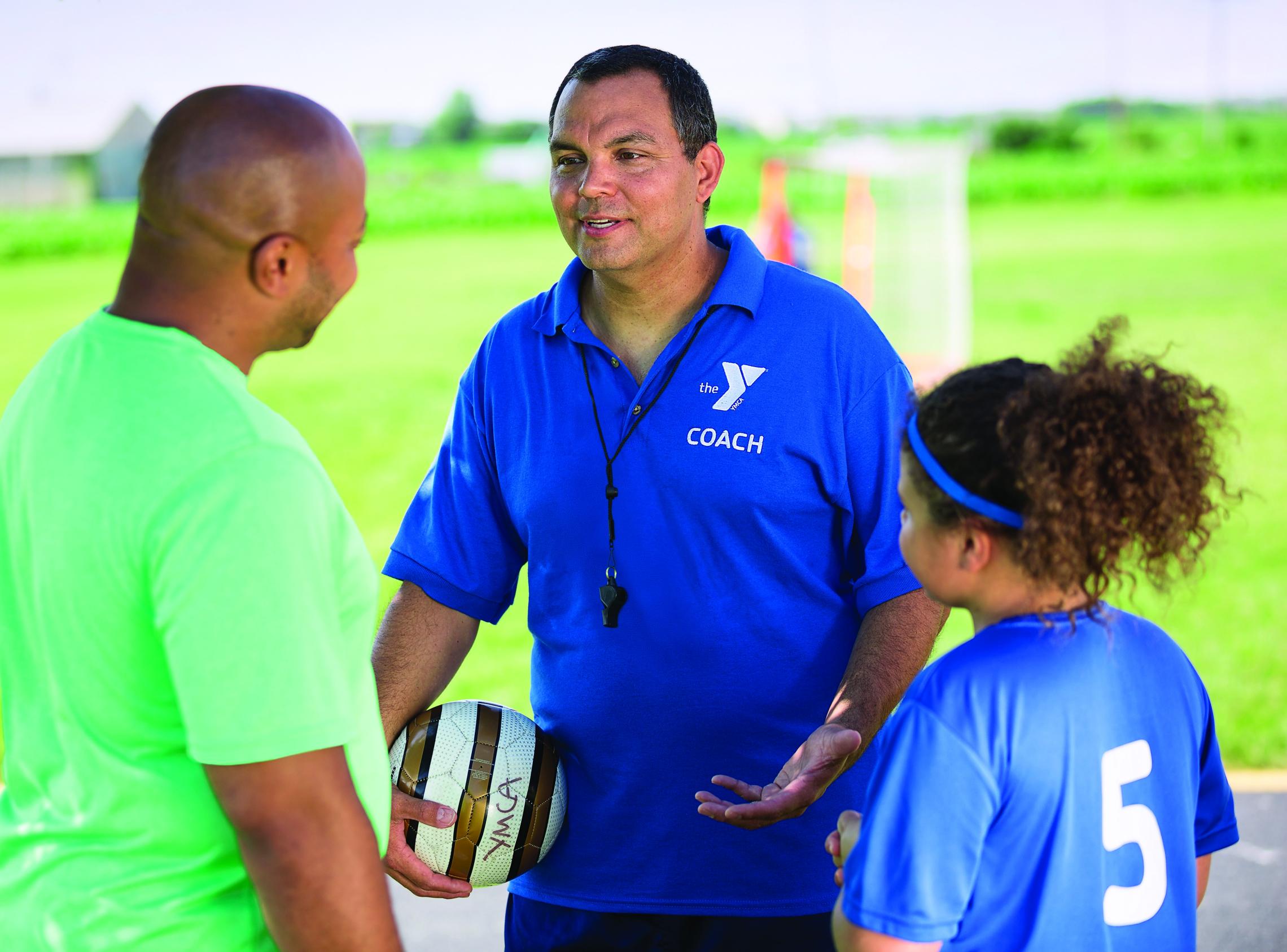 Soccer coach meets with student athlete and parent to discuss the game at the YMCA