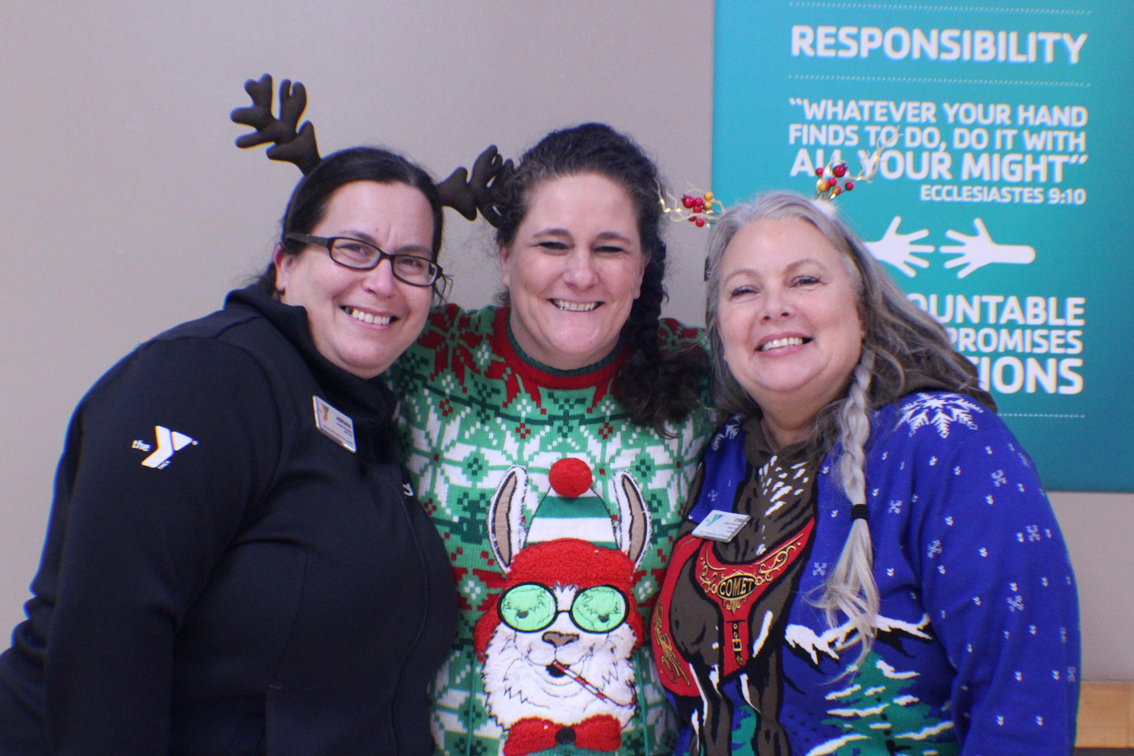 Child Care staff post in festive holiday sweaters and reindeer antlers at the YMCA