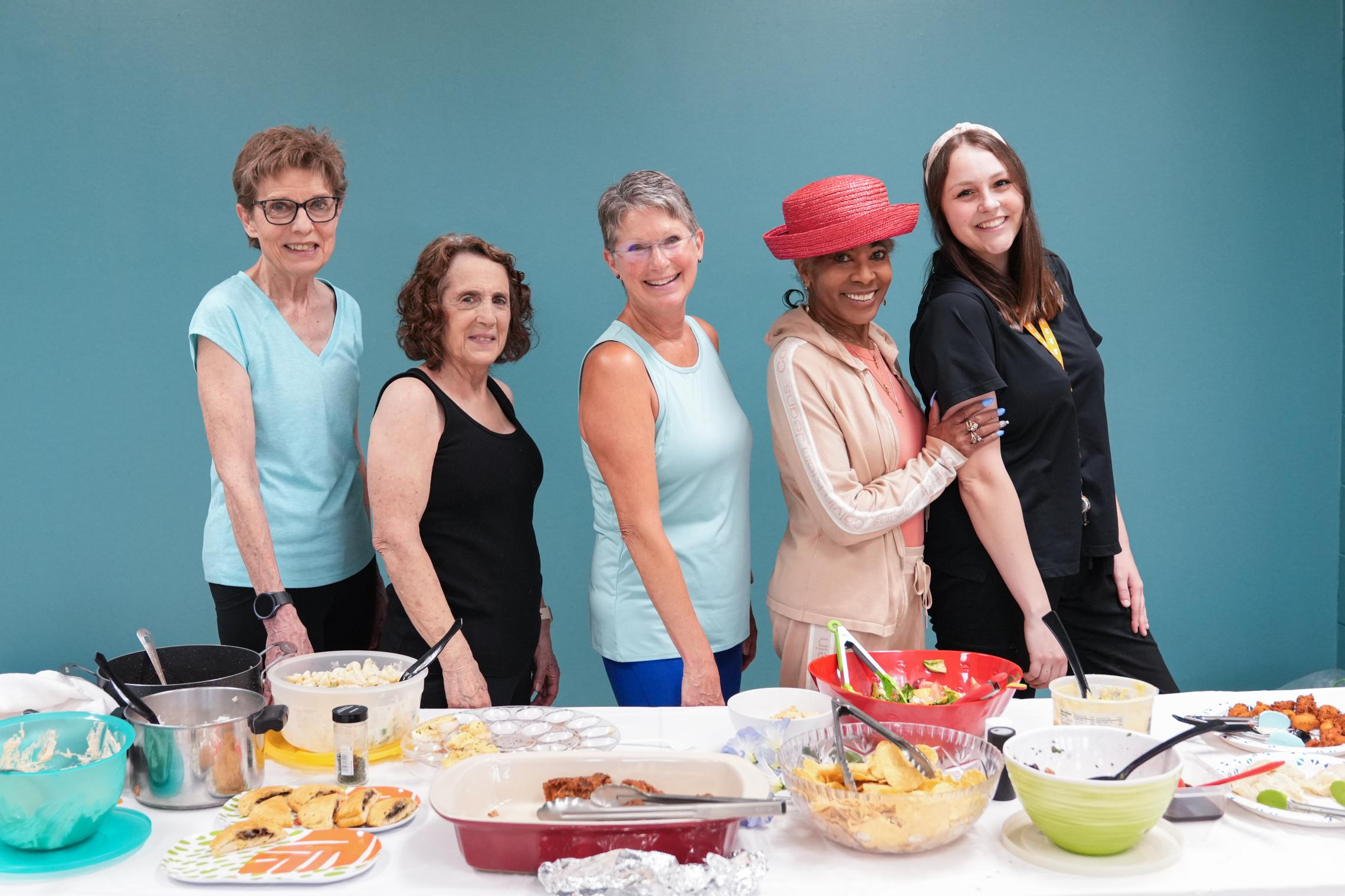 A group of five women in front of a potluck table
