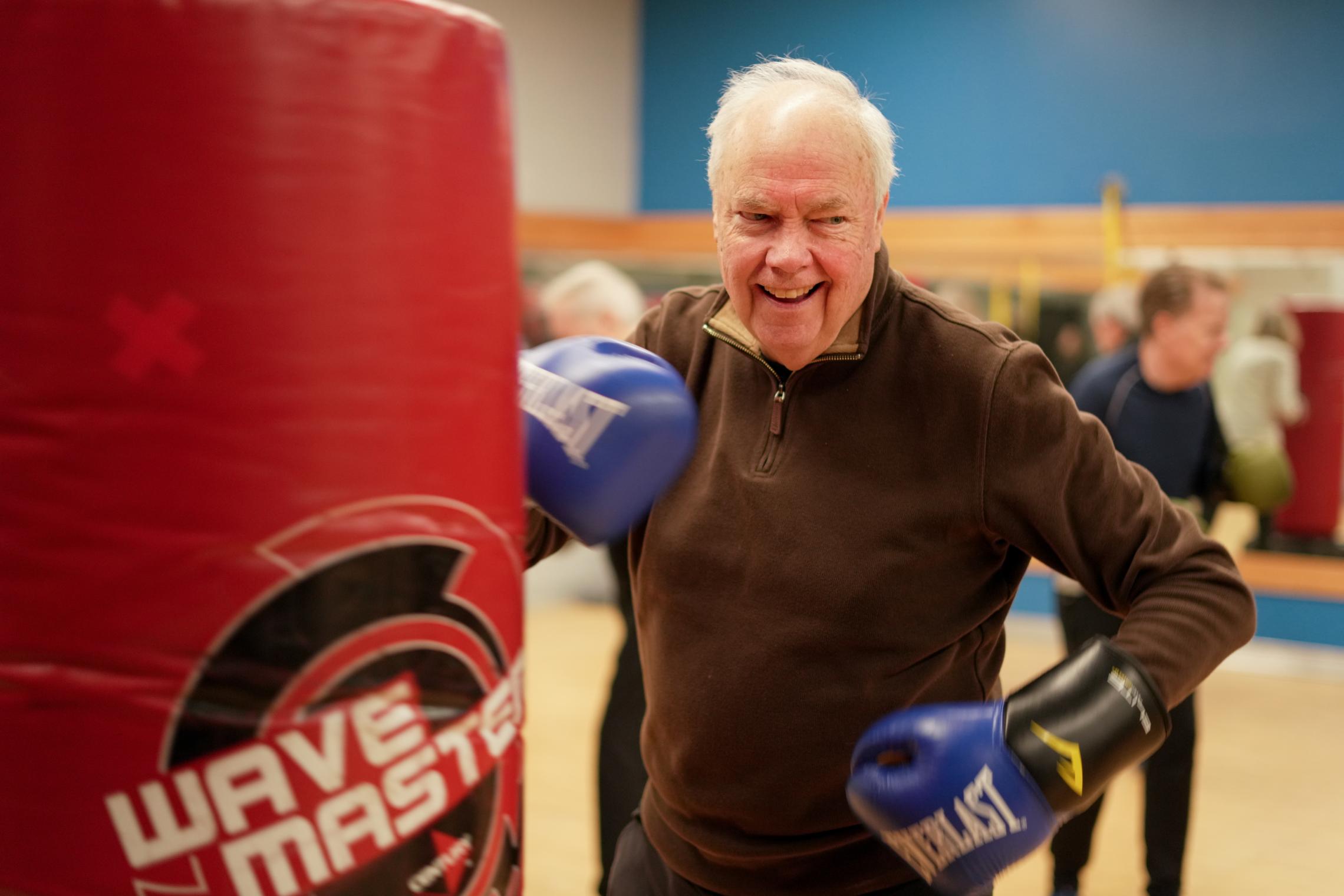 A Rock Steady Boxing participant punching a bag