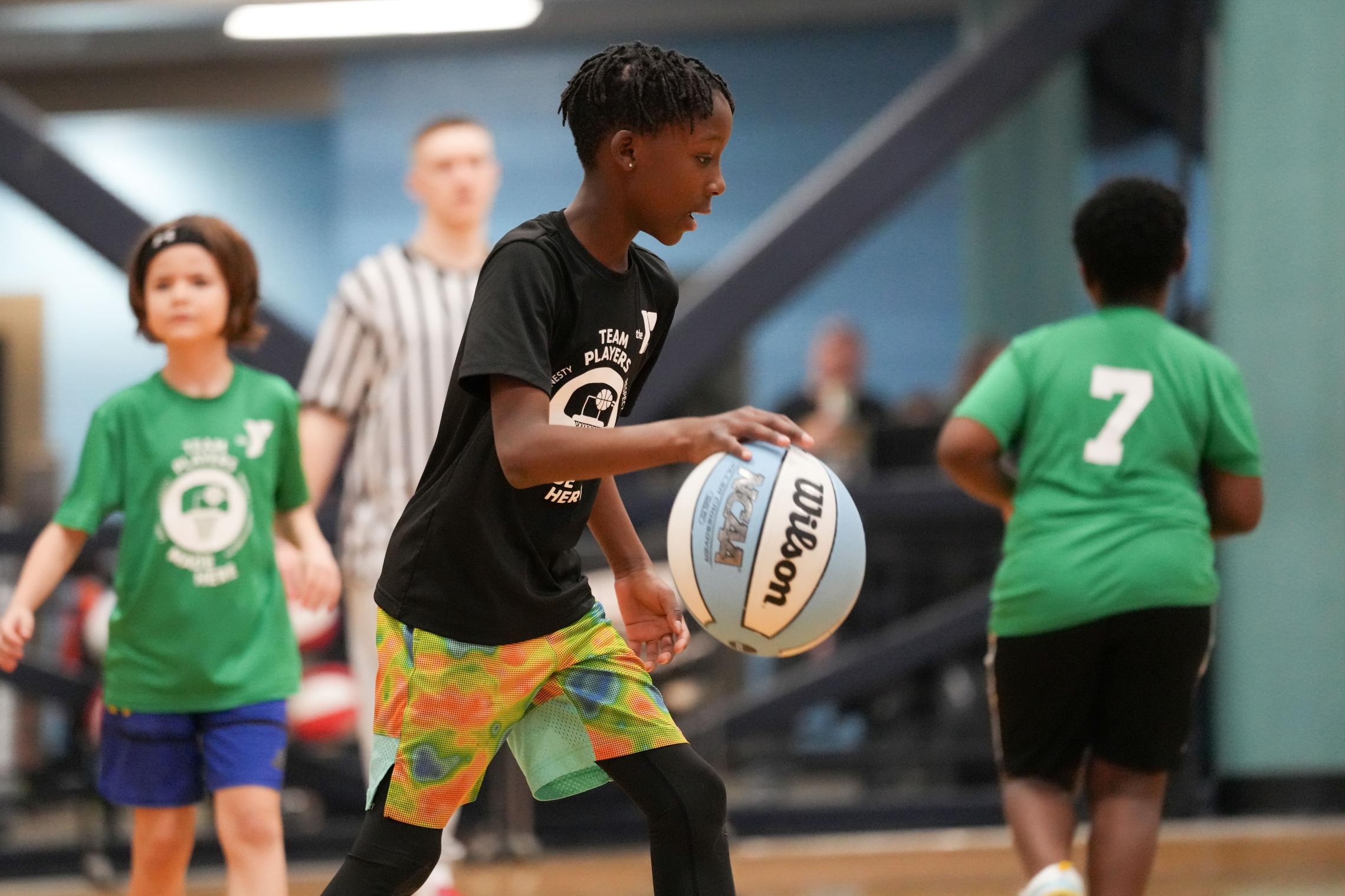 Youth basketball player dribbling a basketball during an indoor YMCA game.