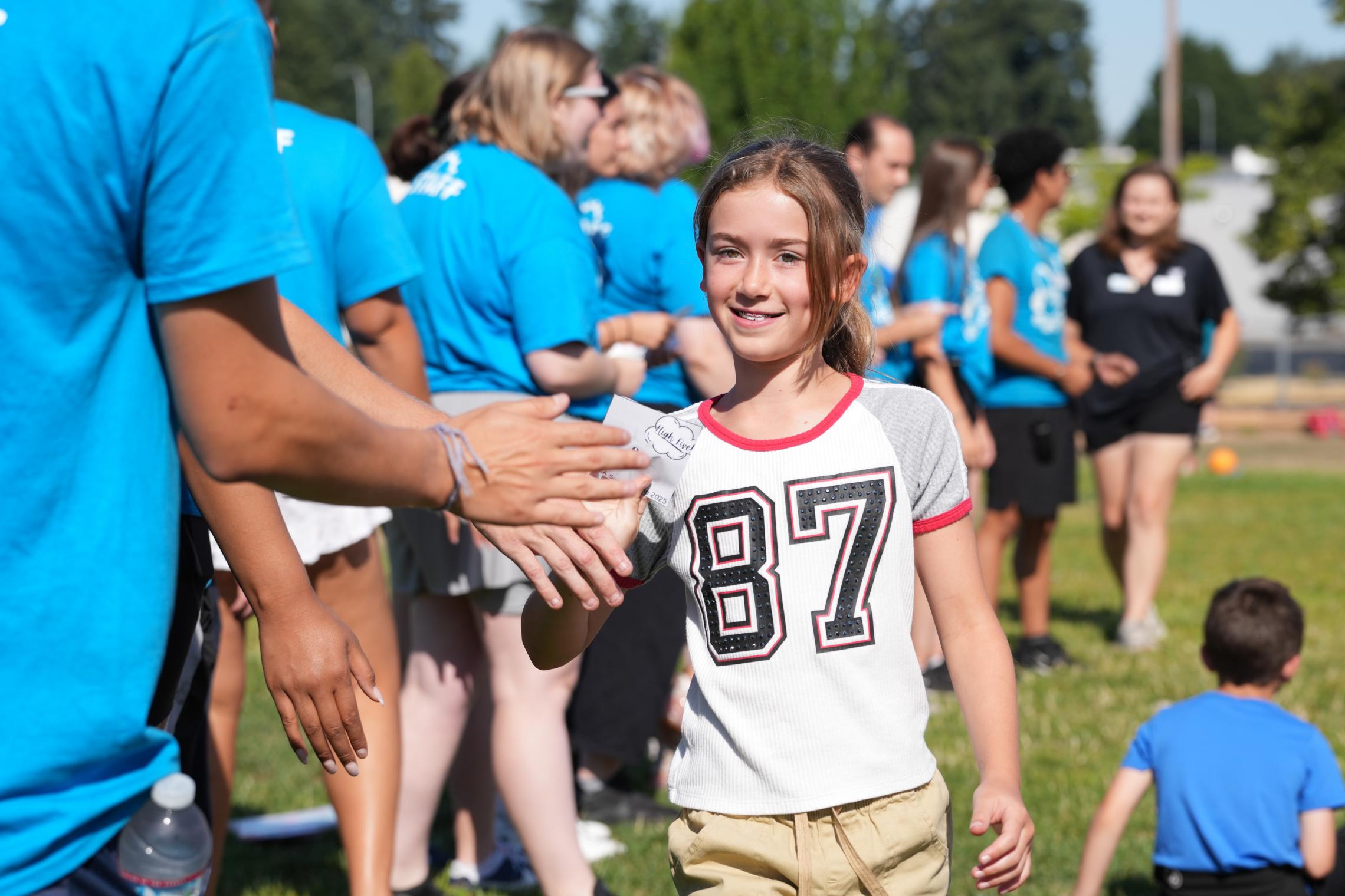 A Y Camper gets high fives from Y Counselors