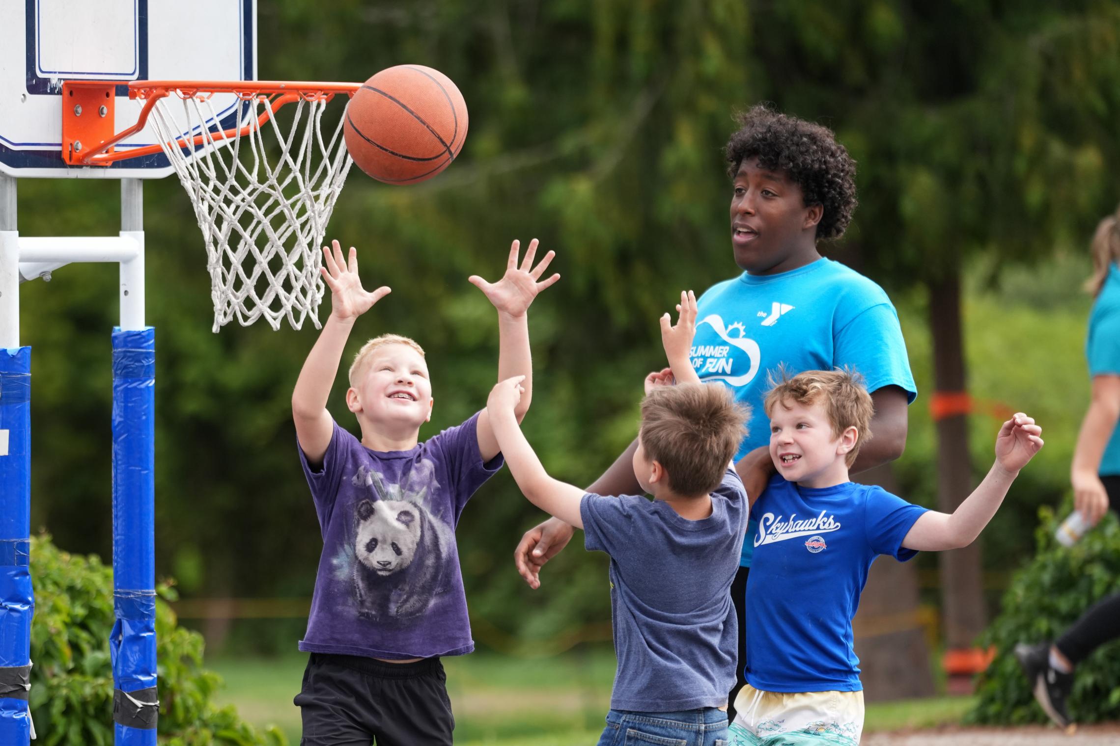Y campers and counselor play basketball