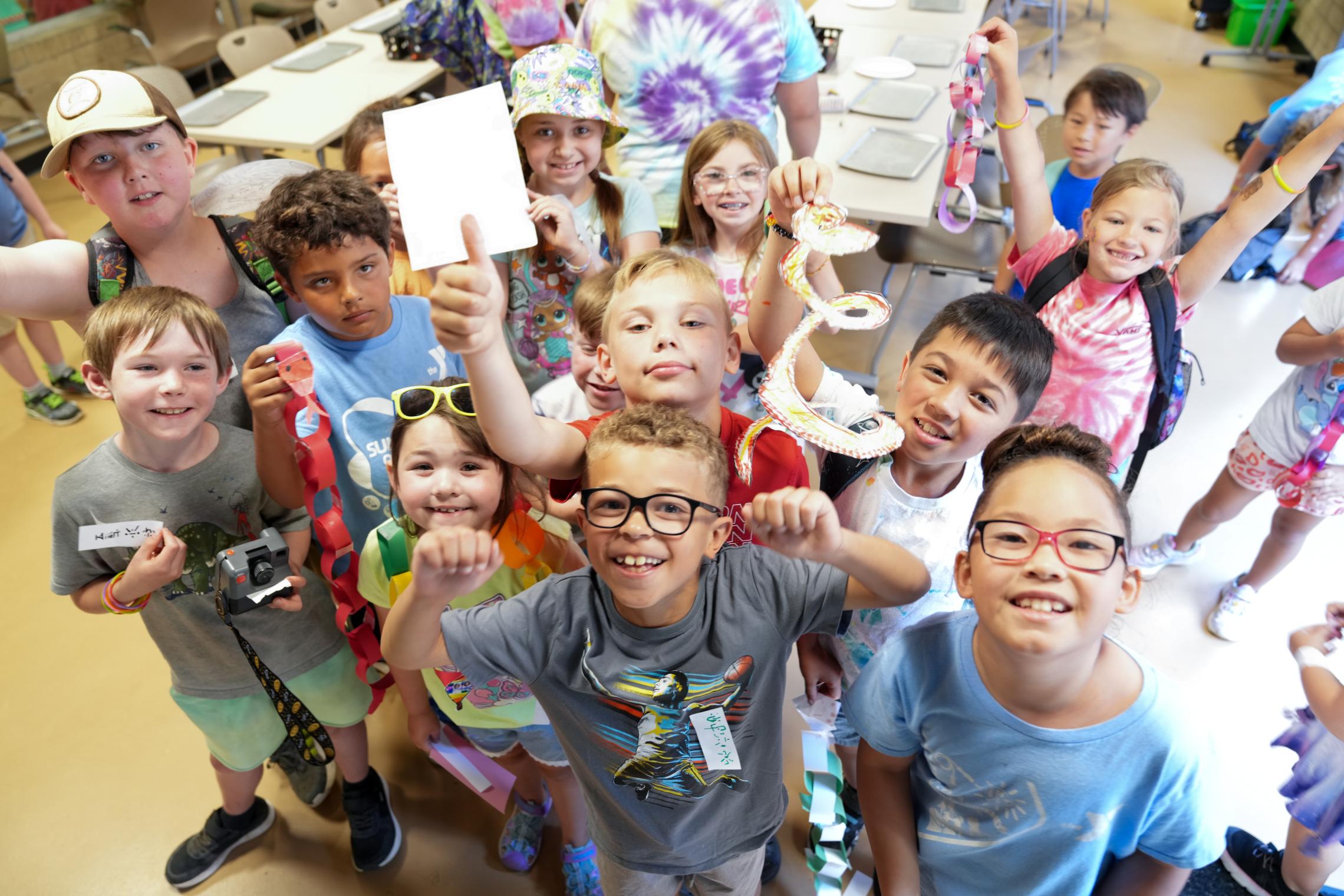 Children at a YMCA summer camp classroom proudly display handmade crafts and activity projects during an indoor enrichment program at the YMCA of Pierce and Kitsap Counties.