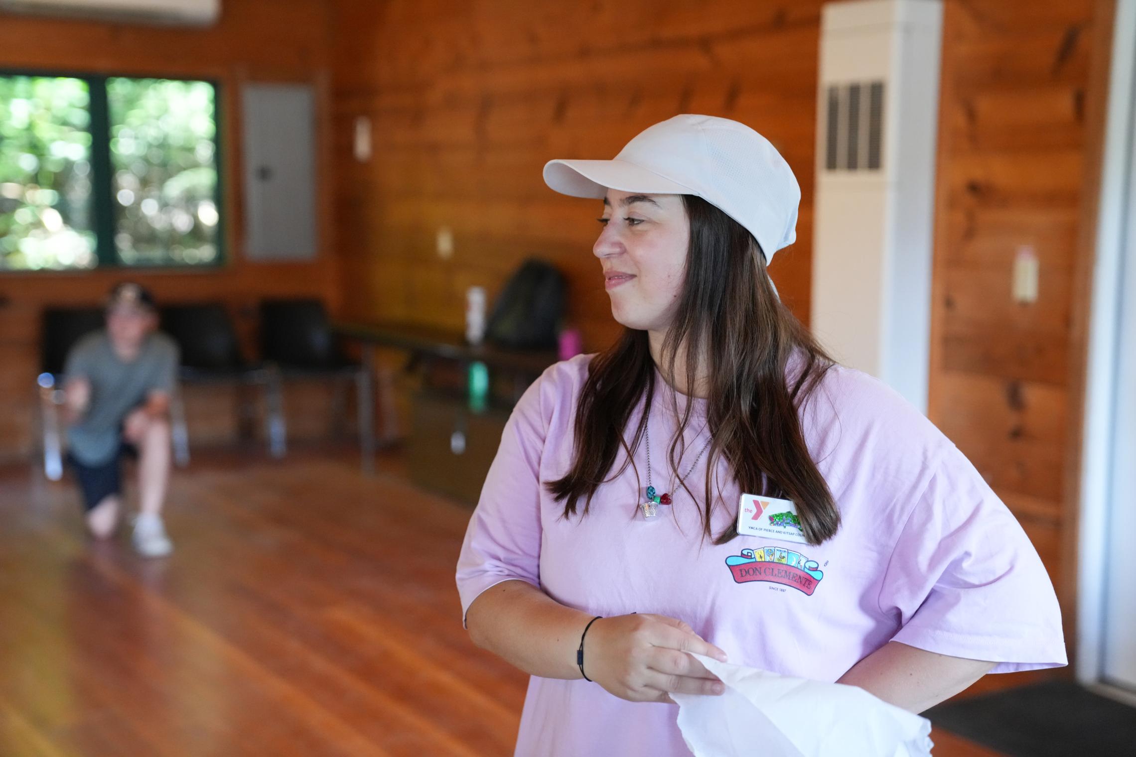 YMCA Kosovo counselor Riga leads a traditional Albanian handkerchief dance activity inside a Camp Seymour lodge, sharing cultural traditions and international friendship with campers.
