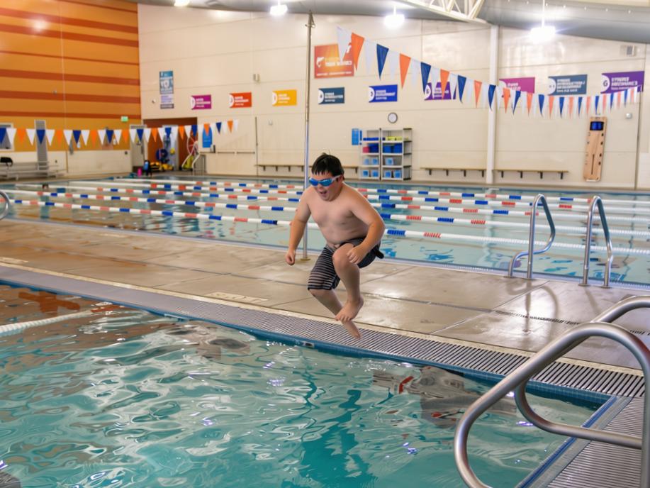 Beary jumps into the pool at the Gordon Family YMCA aquatic center, demonstrating confidence and water skills gained through YMCA swim lessons.