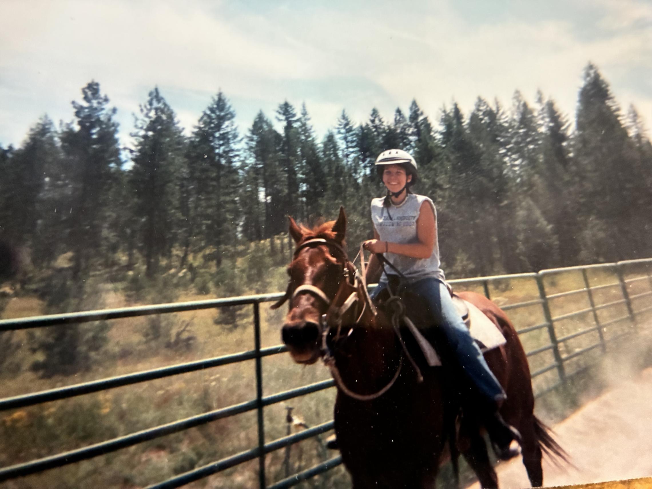 Katie Buckley-Jones rides a horse during YMCA Camp Reed as a child, reflecting the camp experiences that sparked a lifelong passion for youth programs and outdoor adventure.