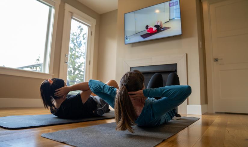 Mother and daughter doing sit ups together at home