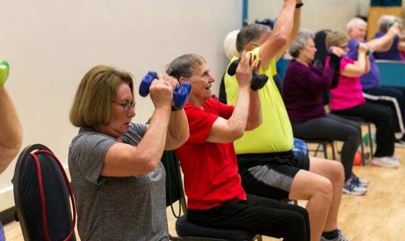 Active older adults lift weights in a senior strength class to improve balance, flexibility, strength, and stability.
