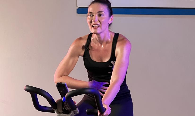 Instructor Jen Garrison sweats and speaks between sprints on a stationary cycling class on YMCA360