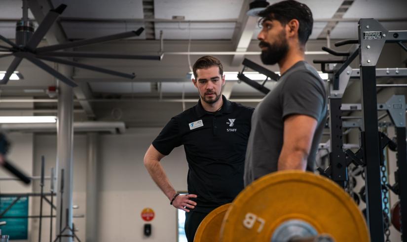KickStart Coach Bryce watches member Benji lift weights to check for his form as part of the KickStart program.