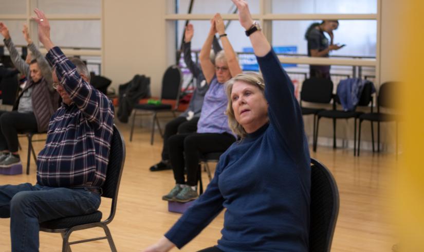 A class of active older adults takes part in chair yoga to help improve balance, flexibility and motion. 