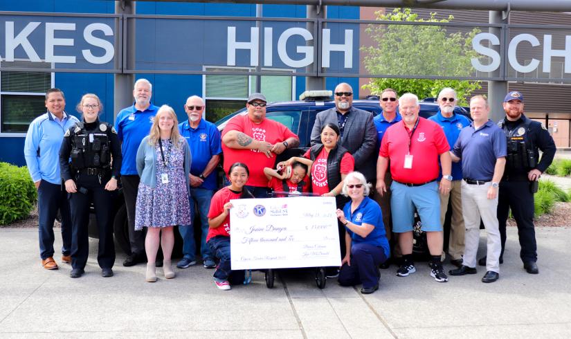 Lakewood community members smiling with a large check raised by the community and the Lakewood Police department at the YMCA