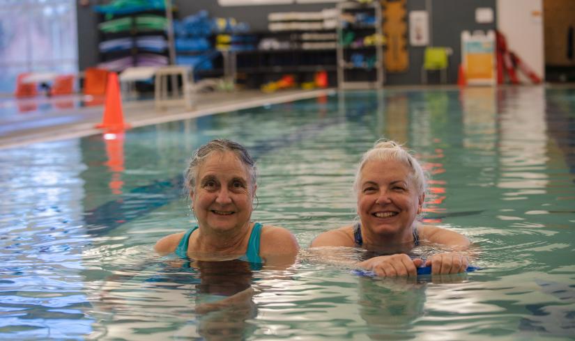 Two people smile in the pool at the YMCA