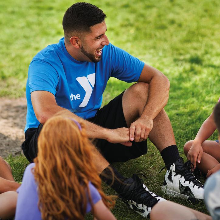 A camp counselor sits with a group of children at the Y
