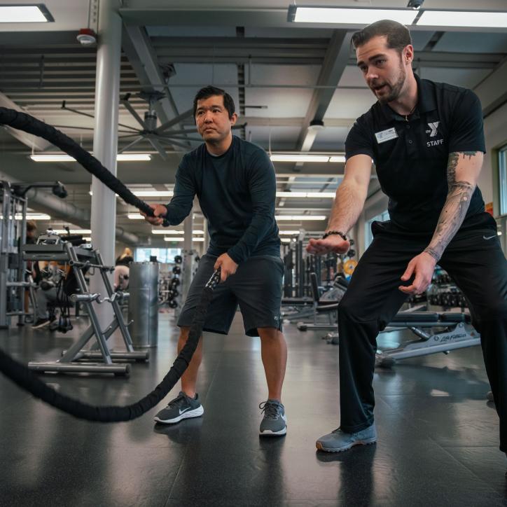 KickStart coach Bryce, provides technique support on the ropes at the University YMCA Student Center to a member.