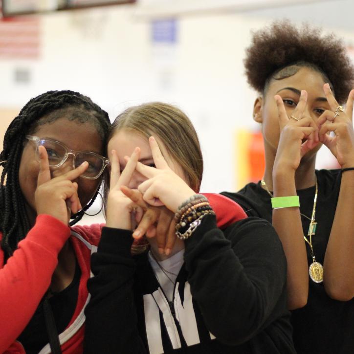 A group of friends flash peace signs while hanging out at Teen Late Nite at the YMCA