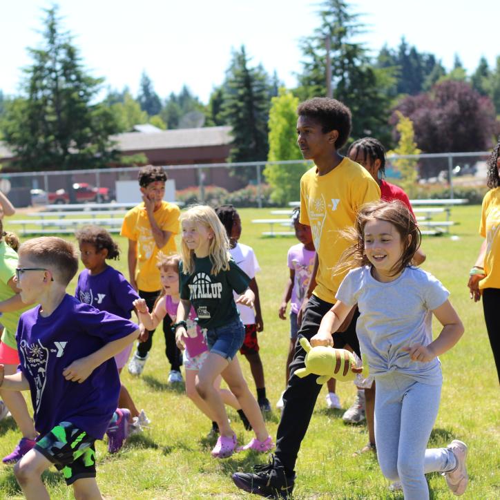 Summer Day Campers running in the field during a camptivity at the YMCA