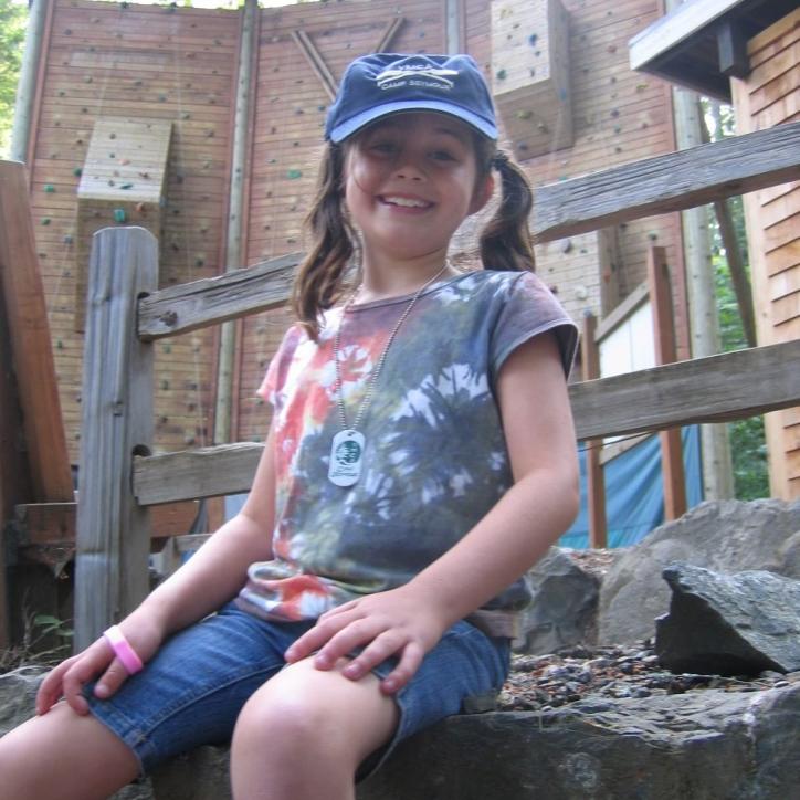 Photo of camper posing in front of the climbing wall at YMCA Camp Seymour