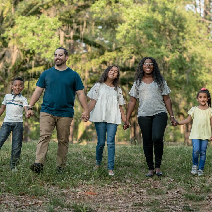 Family Holding Hands In The Park