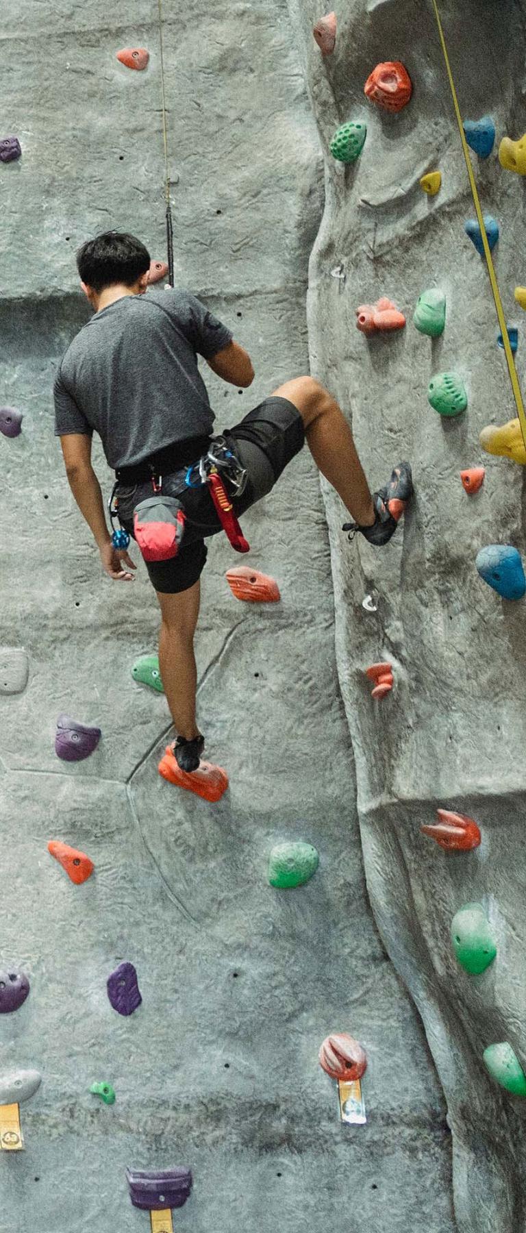 Man Scaling Rock Climbing Wall