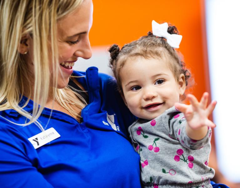 Child Care staff holding smiling baby