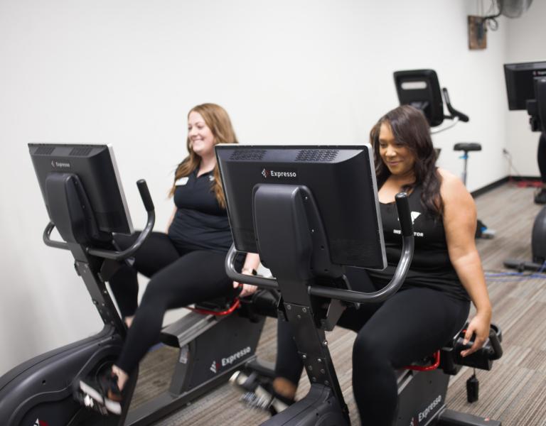 Two Y members using the Expresso cycling machines
