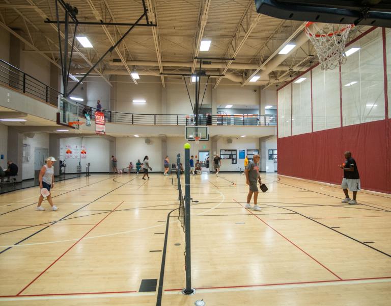 Wide shot of two pickleball courts in the Y's gym