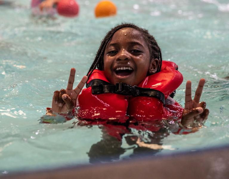 Camper in life jacket showing a peace sign