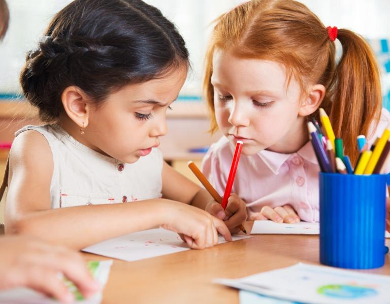 Image of 2 pre-k students coloring with markers