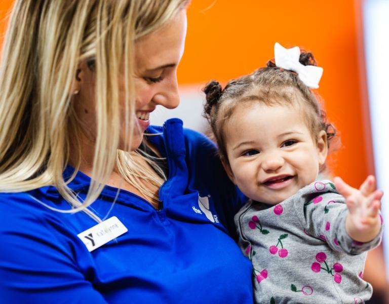 Infant Care staff holding smiling baby