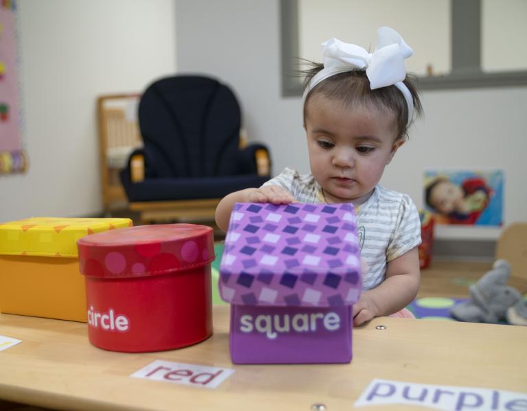 Infant engaging with the colors and shapes of different boxes