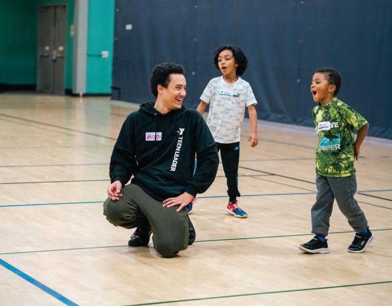 Kids night out teen leader leads a game in the middle of the gym