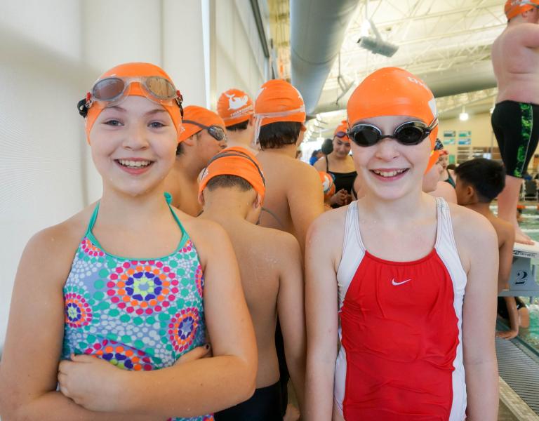 Swim team members pose for a photo poolside