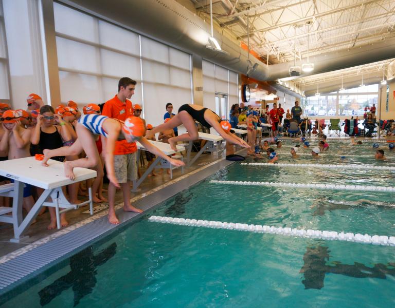 Gordon tiger sharks diving into the lap pool at a swim meet at the YMCA