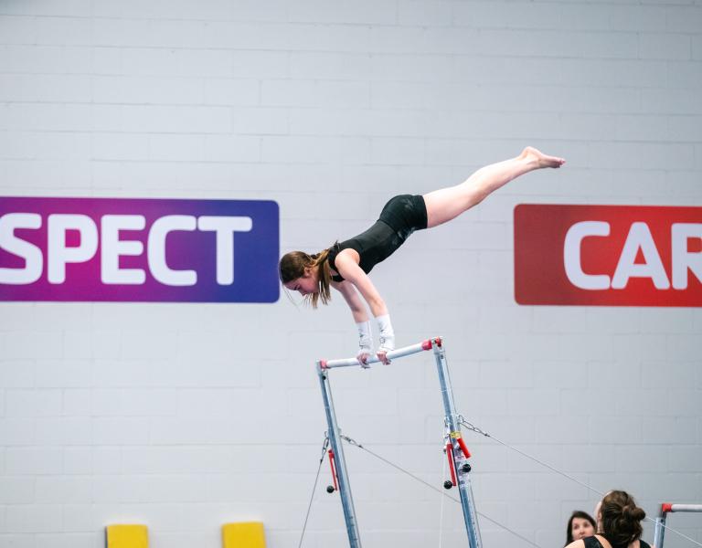 Gymnastics participant performing a routine on the bar at the YMCA