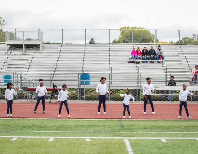 Youth Cheerleading participants practice a routine on the outdoor track at the YMCA