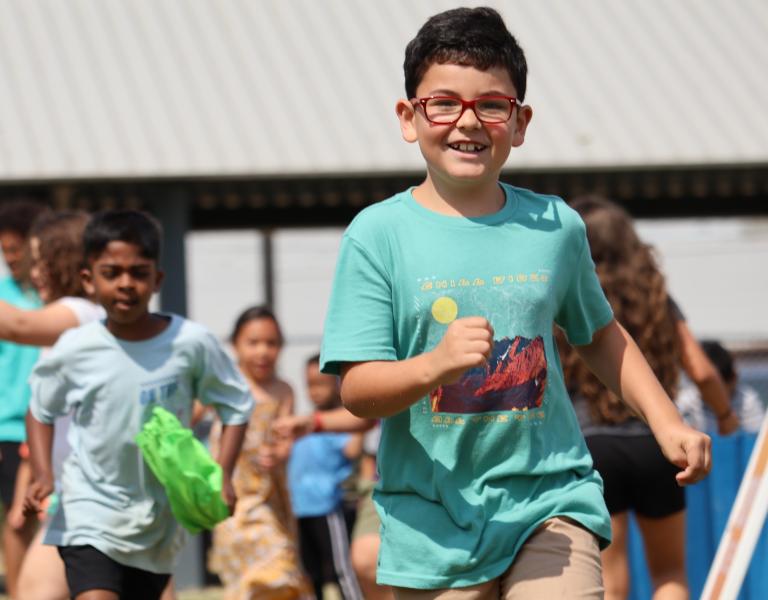 Campers run in the outdoor field at the YMCA during game time.