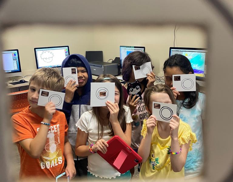 Photography students pose with cardboard cameras during a class session at the YMCA